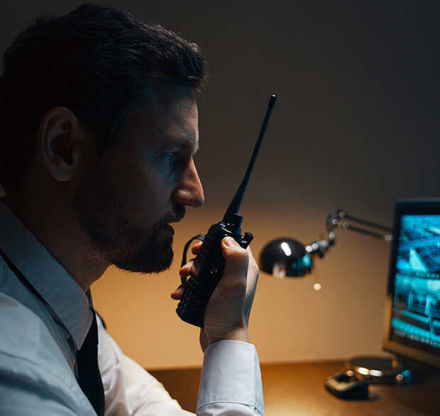Security agent talking on radio and looking at computer screen